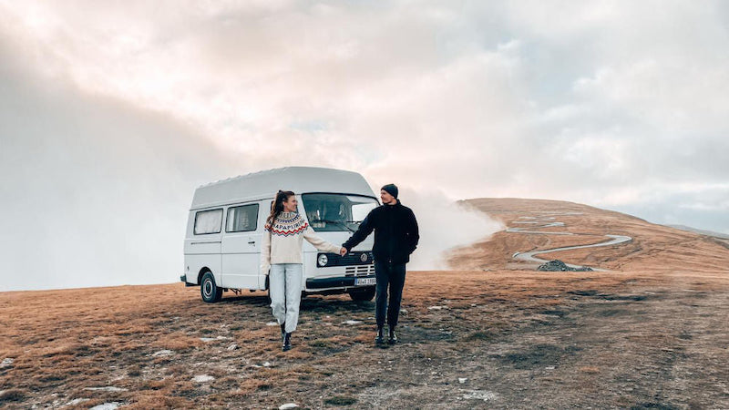 Couple holding hands walking in front of van