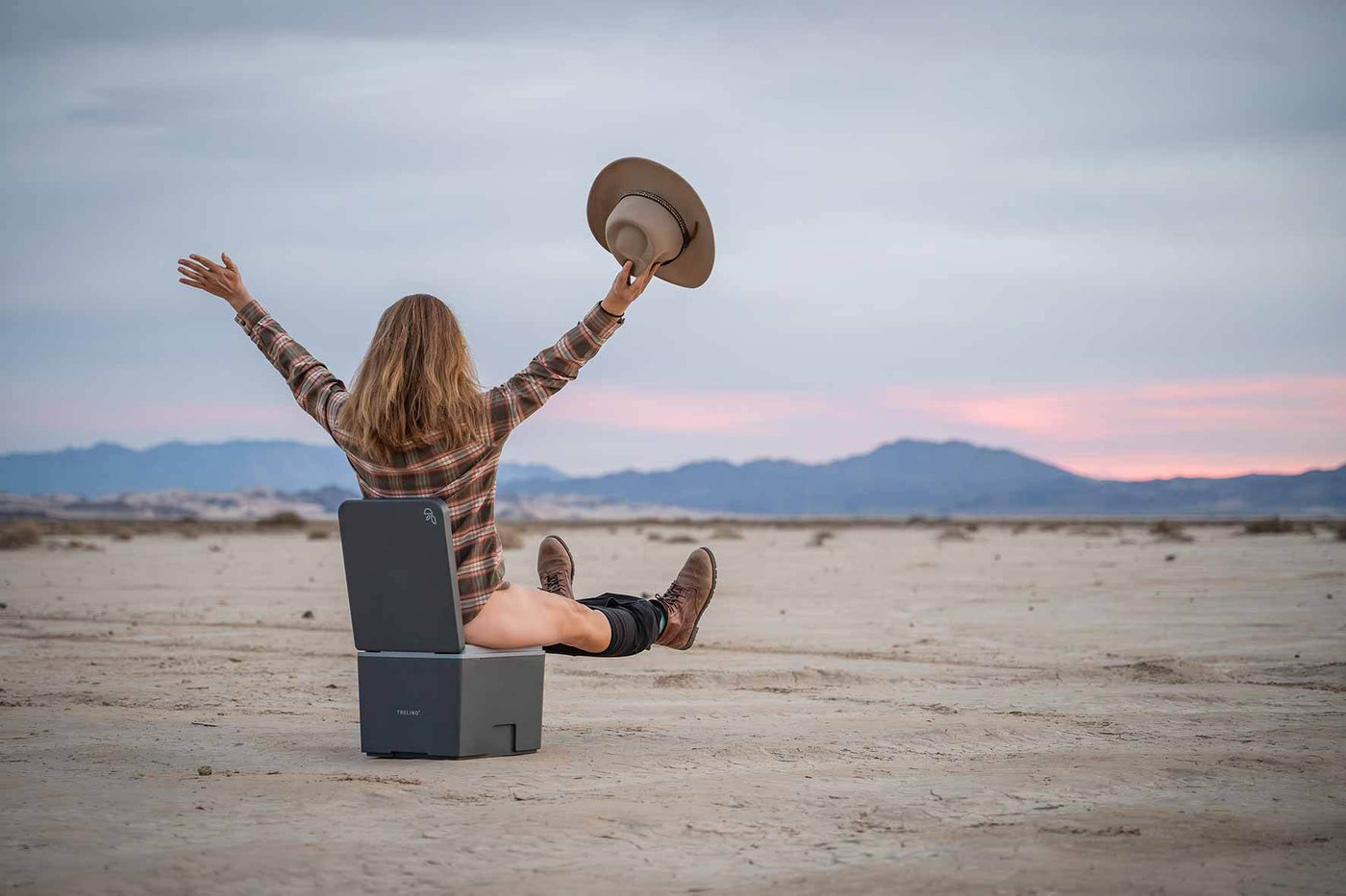 Women sit on a Trelino Evo S Composting toilet in a dessert and is happy.