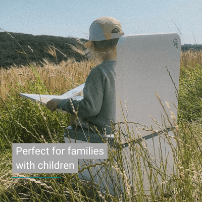 A young child reads in a field, seated on a white chair by a Trelino® Evo Urinometer.